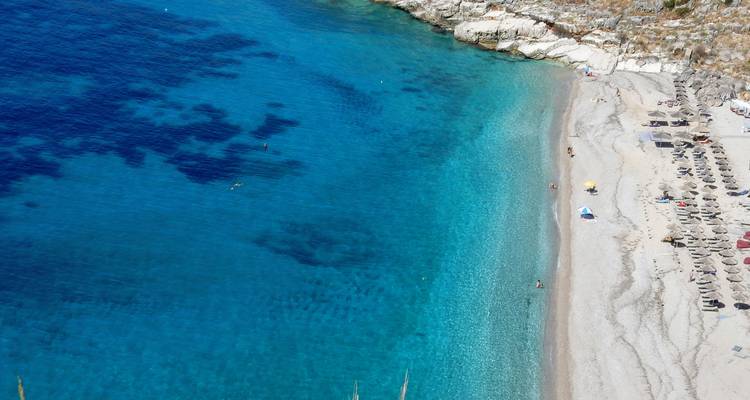 Clear turquoise water and sandy beach with umbrellas.