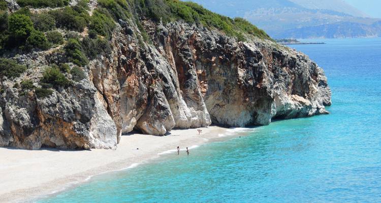 Rocky beach with turquoise water and cliffs.