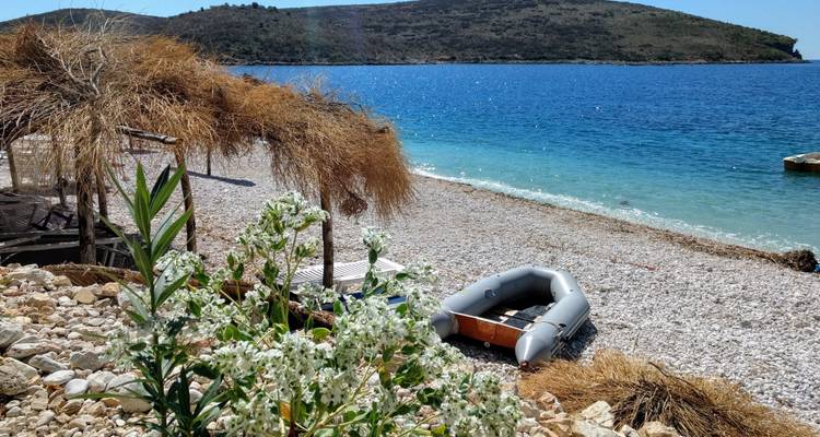 A small inflatable boat on a rocky beach with a view of the sea.