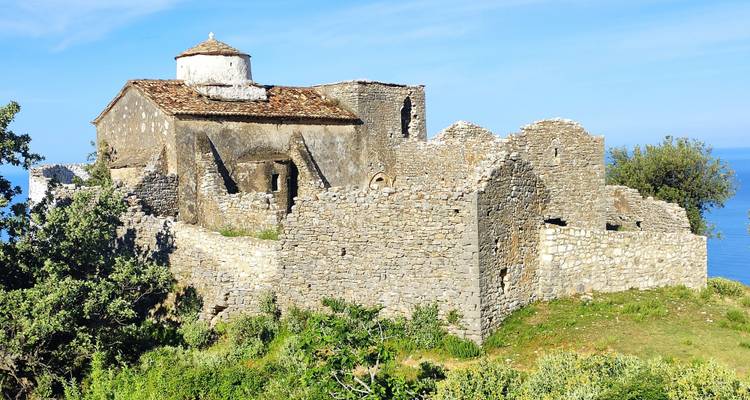 Ancient stone structure near the coast with blue sea in the background.