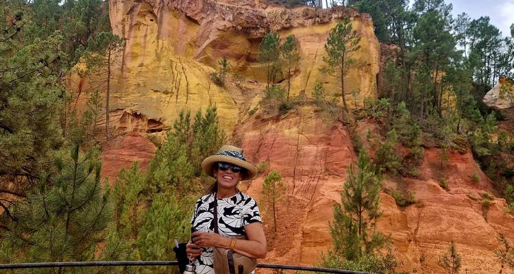 Femme posant devant une formation rocheuse colorée dans un espace naturel.