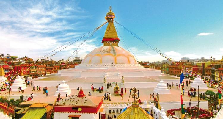 Kleurrijke stupa met vlaggen en omringende structuren.