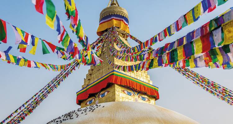 Kleurrijke stupa met gebedsvlaggen tegen een heldere hemel.