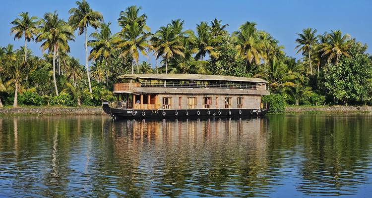 Woonboot op een rivier met palmbomen op de achtergrond