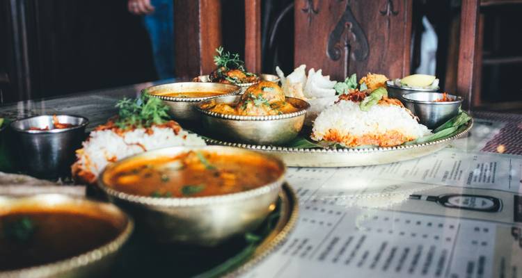 Traditionelle südindische Mahlzeit, serviert auf kunstvollen Messingplatten mit Currys, Reis und Würzmitteln.