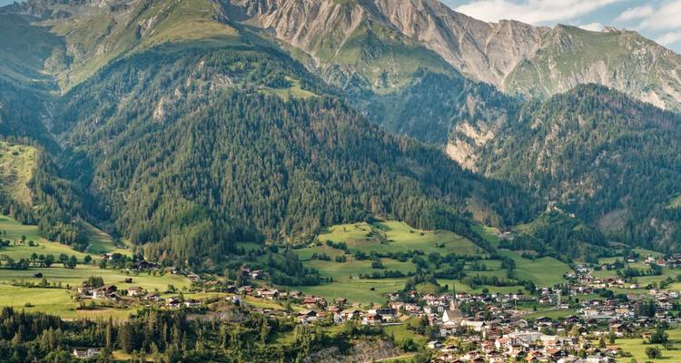 Dorf eingebettet in ein üppiges Tal, umgeben von Bergen.