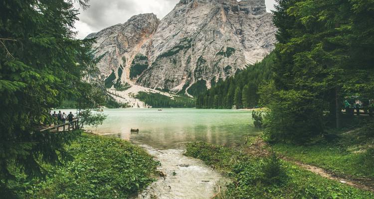Grüne Berglandschaft mit einem See und Menschen, die herumspazieren.