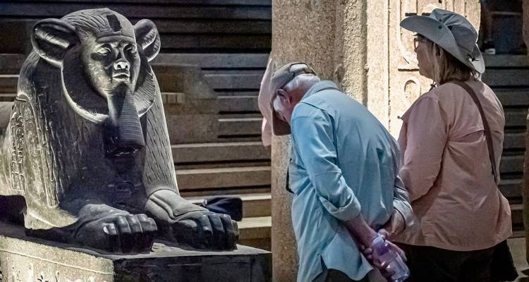 Dos personas observando una estatua egipcia dentro del museo.