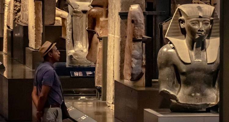 Un hombre observando estatuas egipcias dentro del museo.