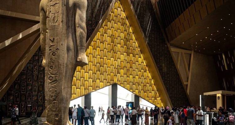 Gran estatua en la entrada del museo con visitantes alrededor.