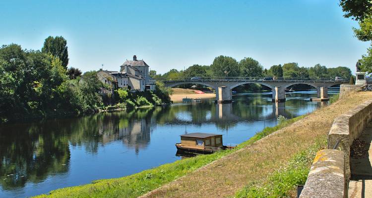 Une rivière avec un pont et des arbres le long des rives.