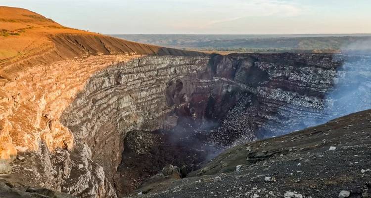 View of a volcanic crater with smoke rising.