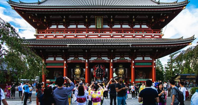 Traditionele Japanse tempel met een menigte bezoekers en kersenbloesems.