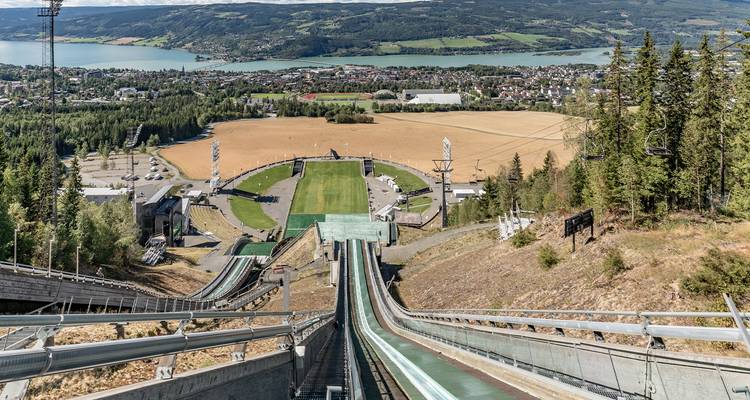 View from a ski jump ramp overlooking a city and lake.