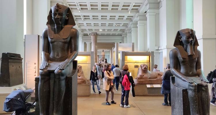 Visiteurs à l'intérieur d'un musée avec des statues de l'Égypte antique.