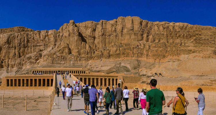 Une foule marchant sur la longue rampe menant au Temple d'Hatchepsout creusé dans les falaises imposantes.