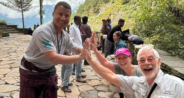 Tourist couple and local guide laughing and giving high fives on a mountain trail.