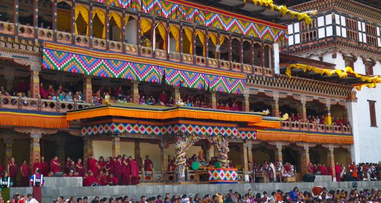 Des foules regardant une danse masquée colorée dans la cour décorée du Punakha Dzong.