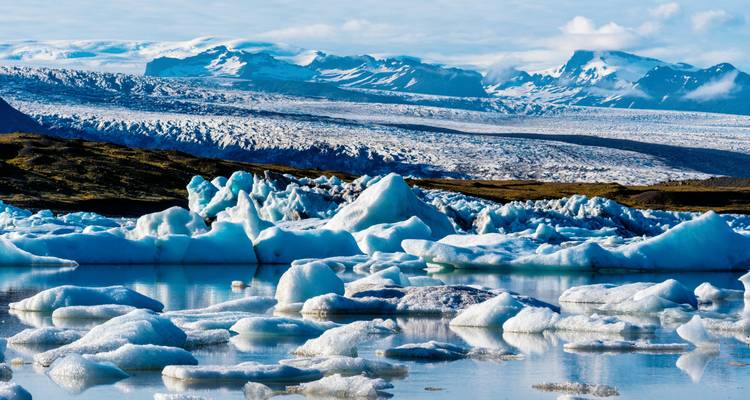 Des icebergs flottant sur un lac serein avec des montagnes en arrière-plan.