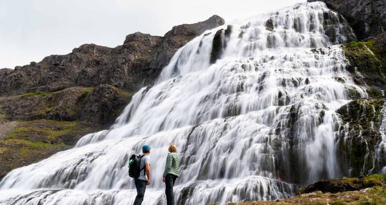 Two people standing in front of a large waterfall.