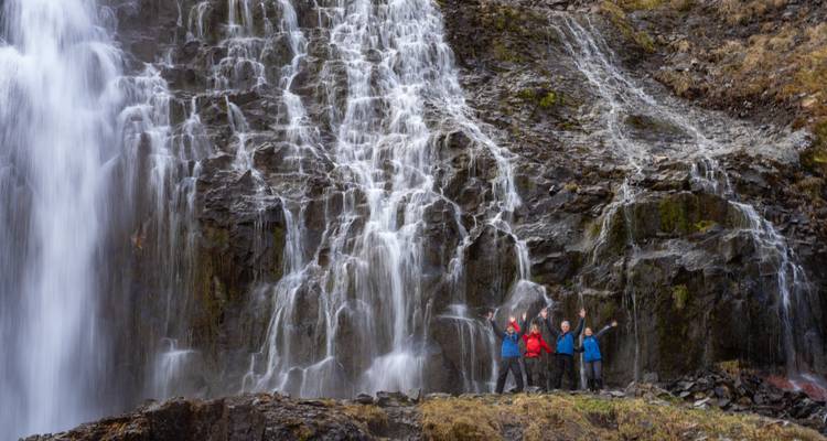 Three people standing cheerfully with a waterfall in the background.