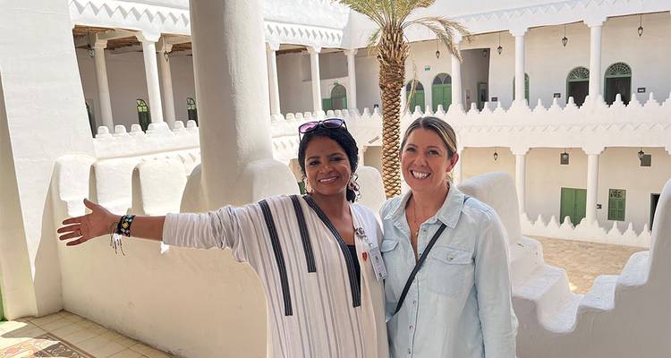 Femmes en vêtements colorés debout à l'intérieur d'un bâtiment traditionnel.
