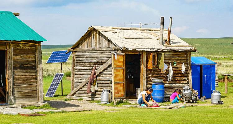 Cabanes en bois rustiques dans une zone rurale avec deux personnes devant.