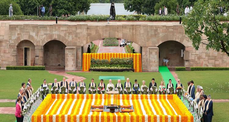 Een herdenkingsplaats met een bloemstuk en mensen die bijeenkomen.