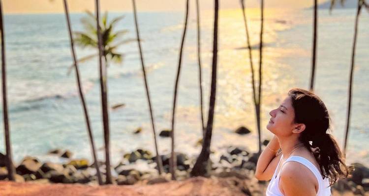 Person enjoying a scenic ocean view with palm trees.