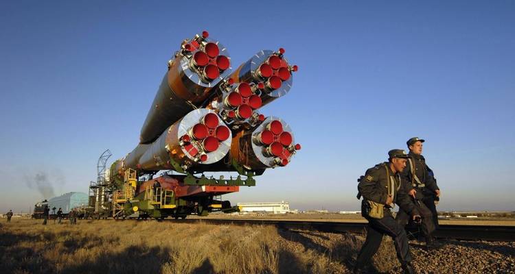 Cohete siendo transportado en vías con personal cerca.