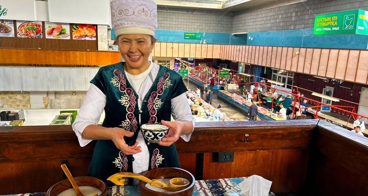 Persona con vestimenta tradicional sirviendo una bebida en un mercado interior.