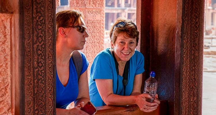 Dos mujeres de pie en una estructura antigua, sonriendo a la cámara.