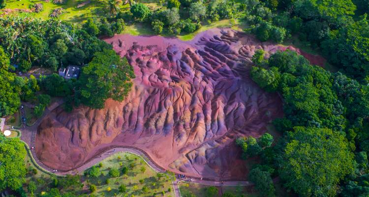 Colorful geological formation surrounded by greenery.