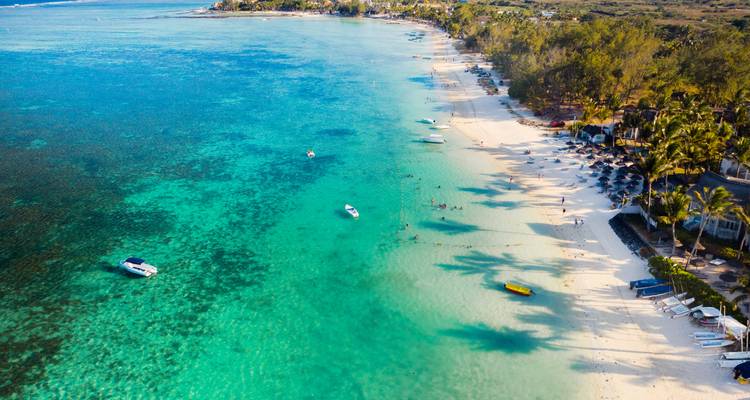 Aerial view of a beach and turquoise sea with some boats.