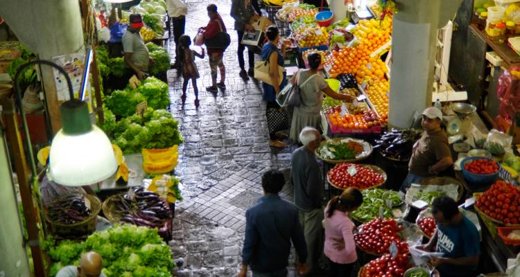 Crowded market with people and vibrant produce.