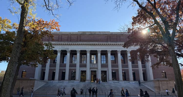 Un bâtiment historique avec des colonnes classiques, des gens marchant devant.