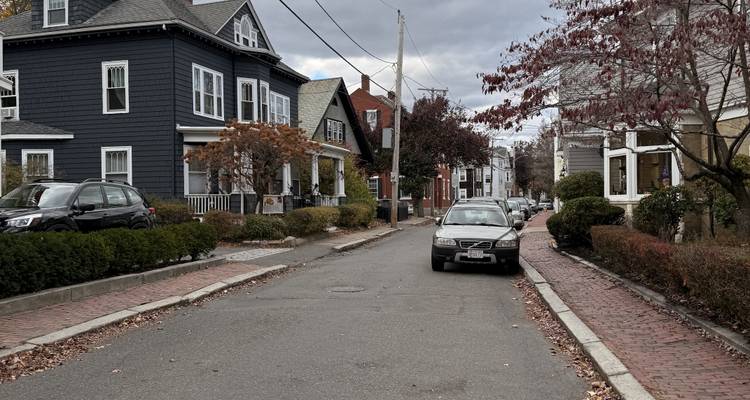 Une rue résidentielle avec des voitures et des maisons historiques.