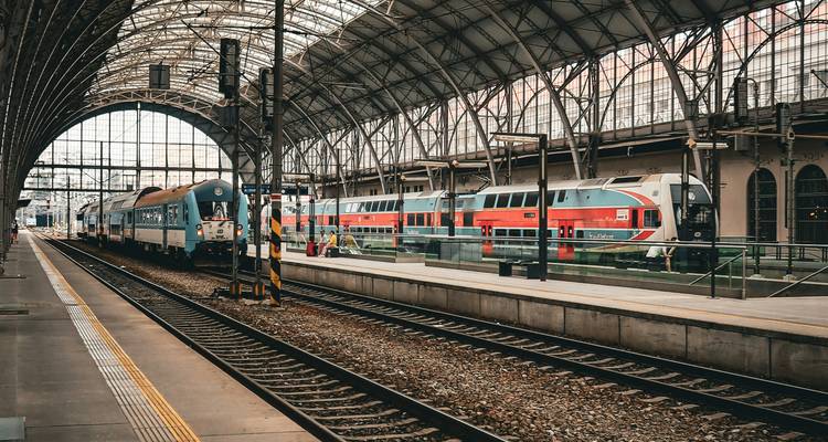 Interior of a train station with trains on parallel tracks.