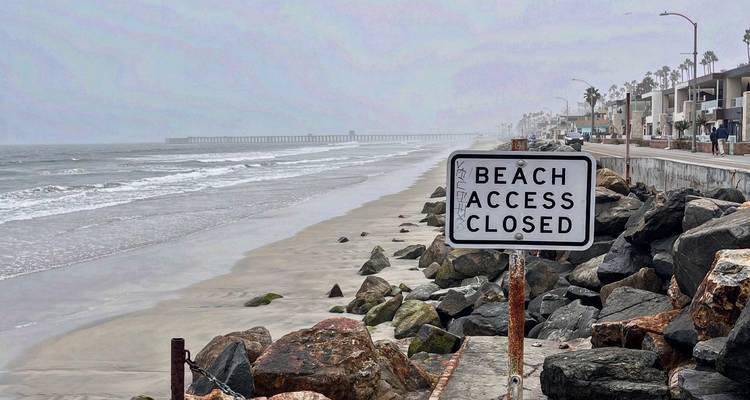 Overcast beach scene with closed access sign.