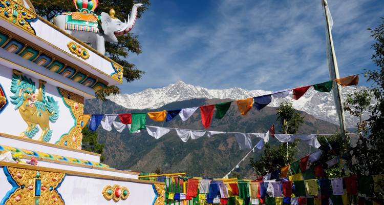 Templo colorido frente al Himalaya con banderas.