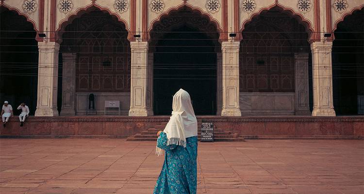 Personnage en tenue traditionnelle devant une architecture moghole.
