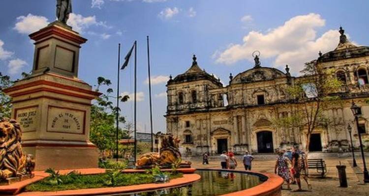 A historical square with a cathedral, statues, and people walking.