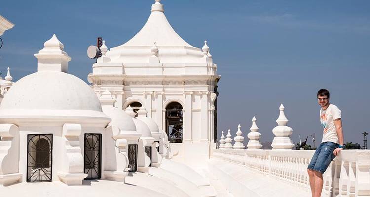 A man posing on the roof of a white building with small domes.