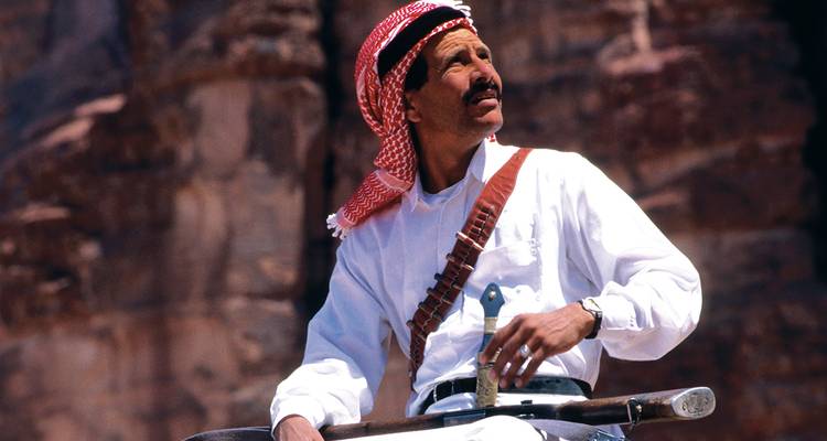 Un homme en tenue traditionnelle posant avec un arrière-plan de rochers.