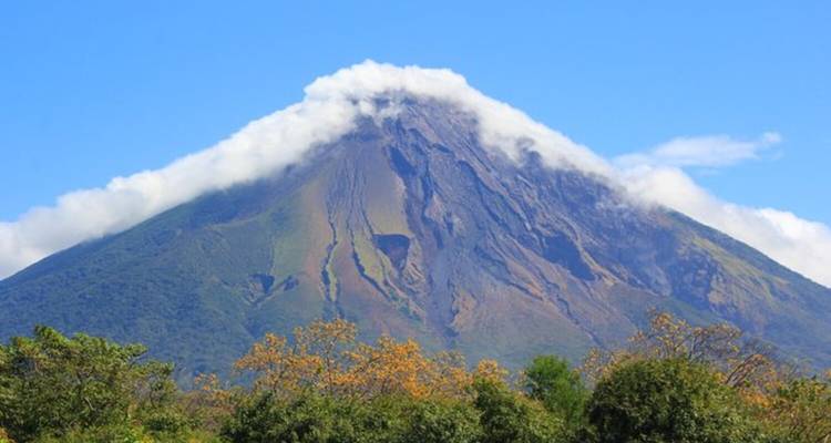 Vulkaan bedekt met wolken aan de top en bossen aan de voet.