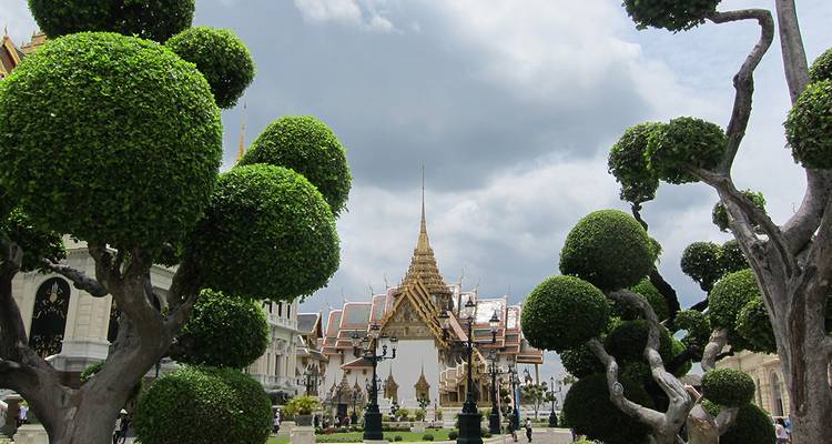 Temple orné entouré d'arbres taillés et de jardins.