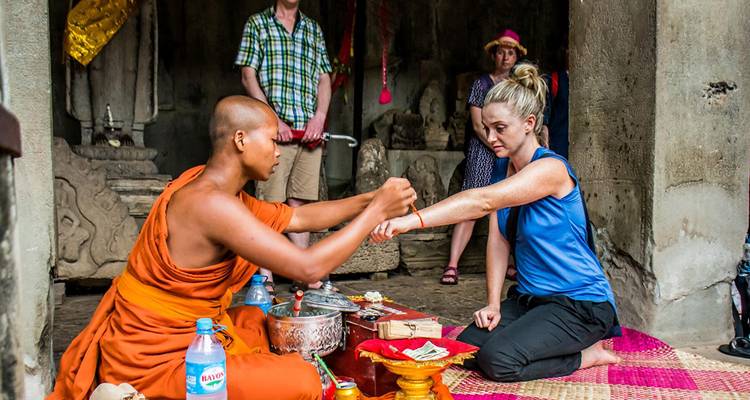Moine effectuant une cérémonie de bénédiction pour un voyageur à l'intérieur d'un temple.