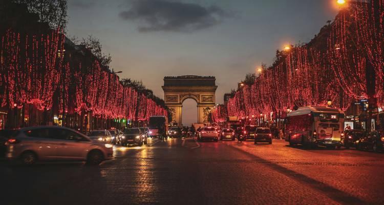 L'Arc de Triomphe la nuit avec des arbres illuminés.