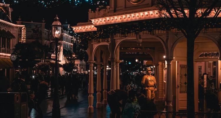 Scène de soirée avec des bâtiments de style victorien et des visiteurs.