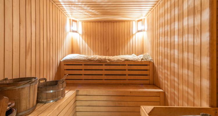 Sauna en bois avec éclairage chaleureux et seau.